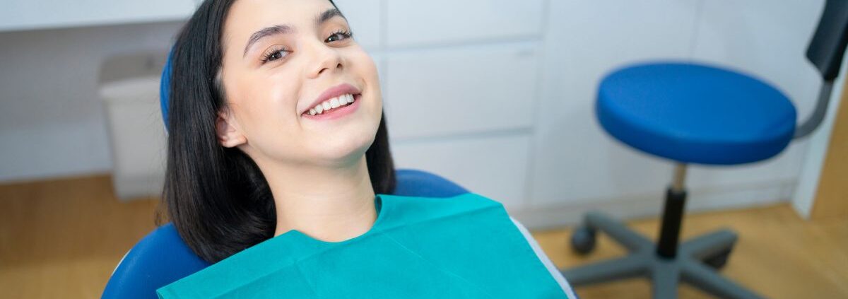 Happy patient in teal bib at Las Cruces dental office showing improved smile results.