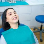 Happy patient in teal bib at Las Cruces dental office showing improved smile results.